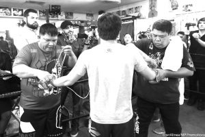 ISINUSUOT ng mga trainor mula sa Team Pacquiao ang gloves kay Manny Pacquiao para sa open workout ng eight-division world champion sa Wild Card gym.  (MP PROMOTION)